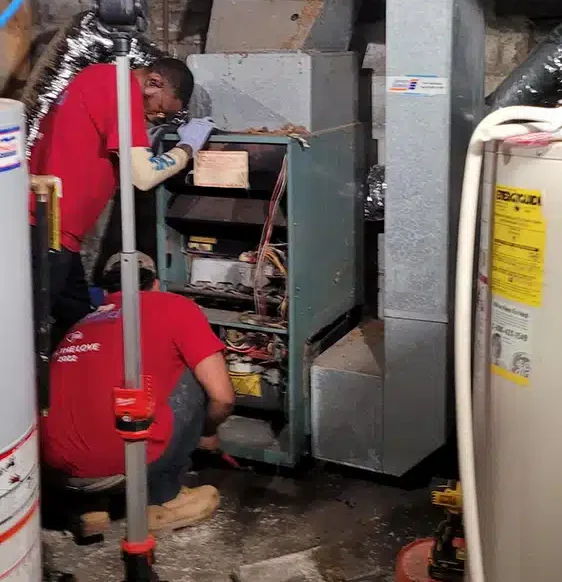 Two Emerald Heating & Cooling techs in Feel the Love shirts installing a new furnace in a Western New York home
