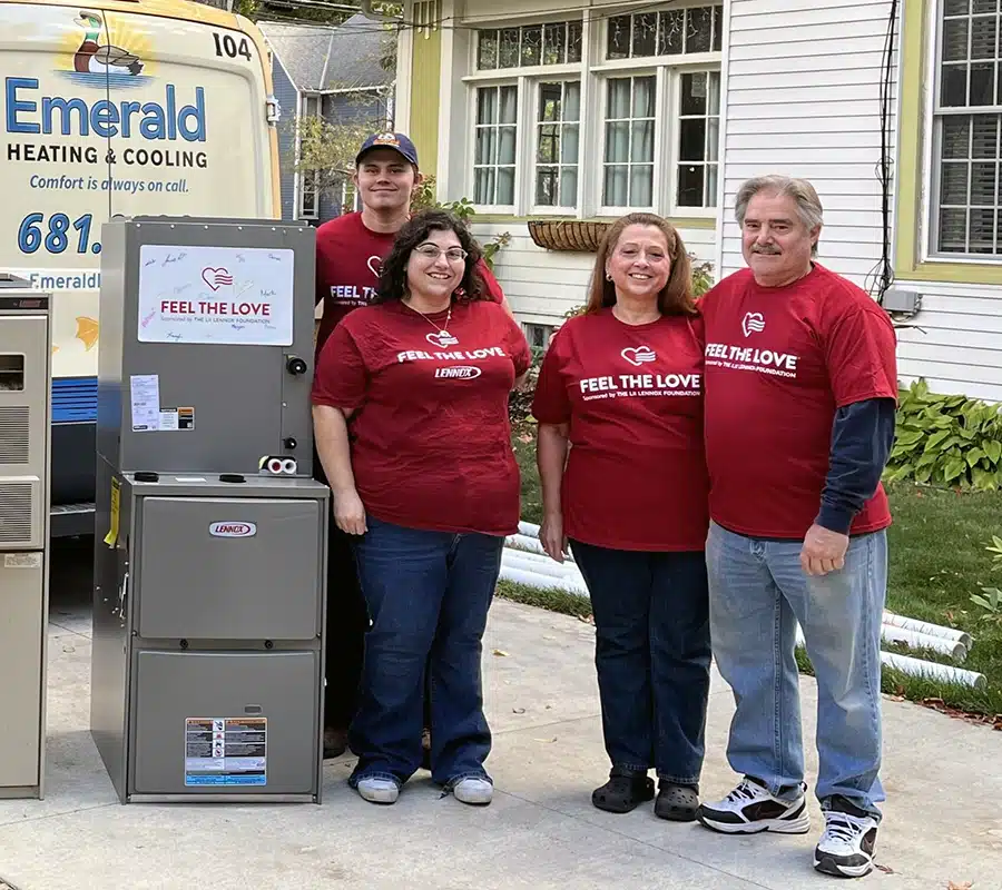 Emerald Heating & Cooling team and Feel the Love recipients smiling beside a new Lennox furnace at a Western NY home.