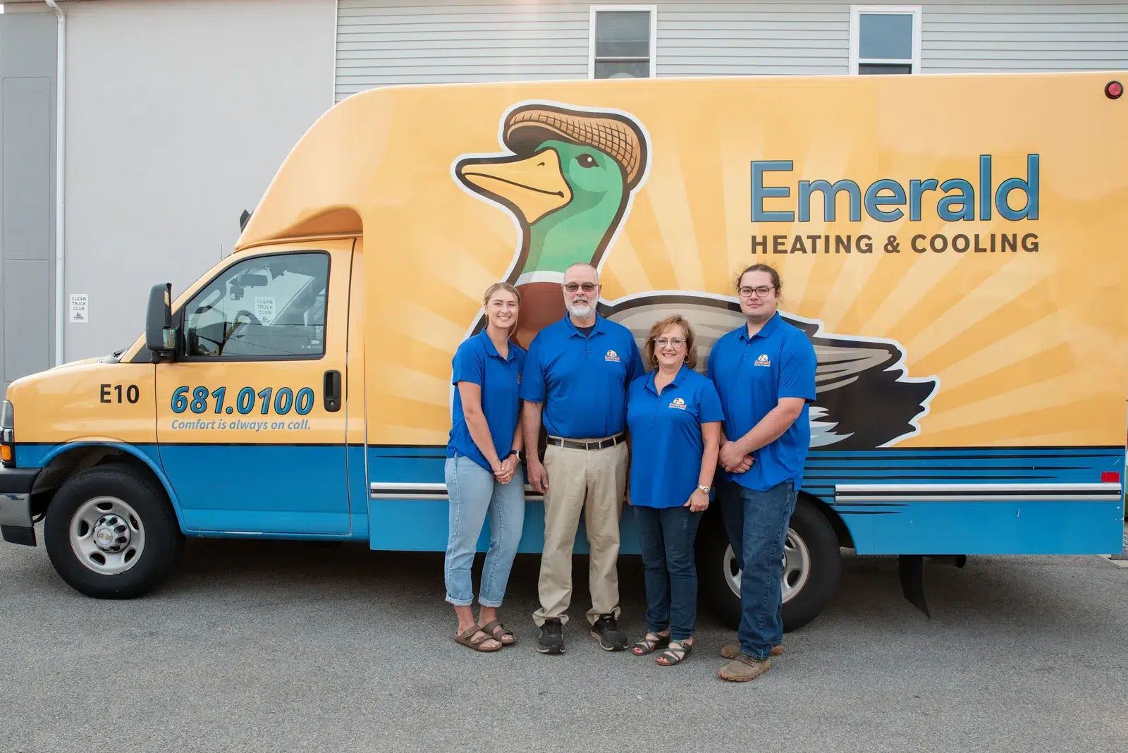 Emerald Heating & Cooling team members standing together in front of a branded service van