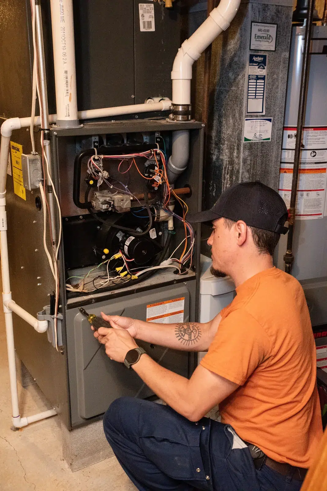 Emerald technician checking wiring inside an open gas furnace during a heating tune-up