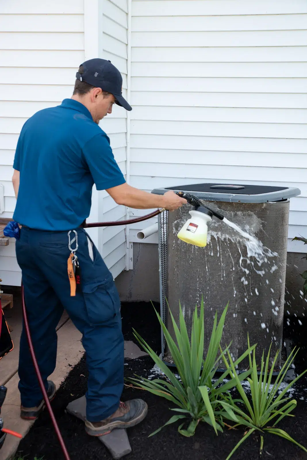 Emerald technician applying coil cleaner to an outdoor air conditioner at a Buffalo area home