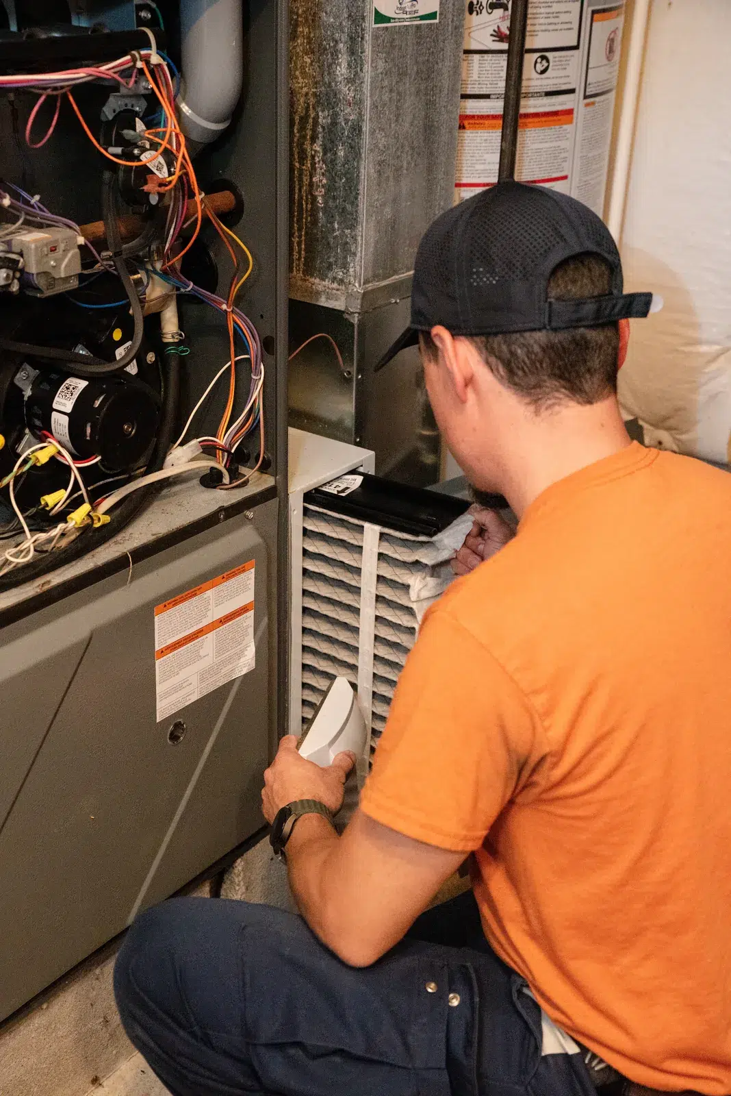 Emerald technician inspecting the burner assembly of a gas furnace in a Western NY basement