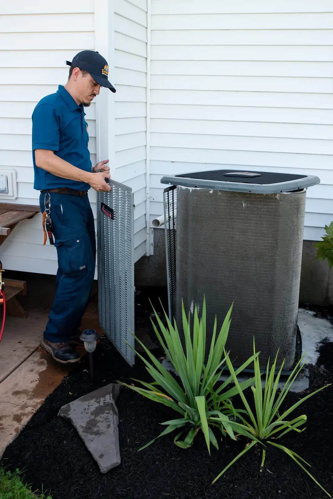 Emerald technician removing the cabinet panel of an outdoor air conditioning unit