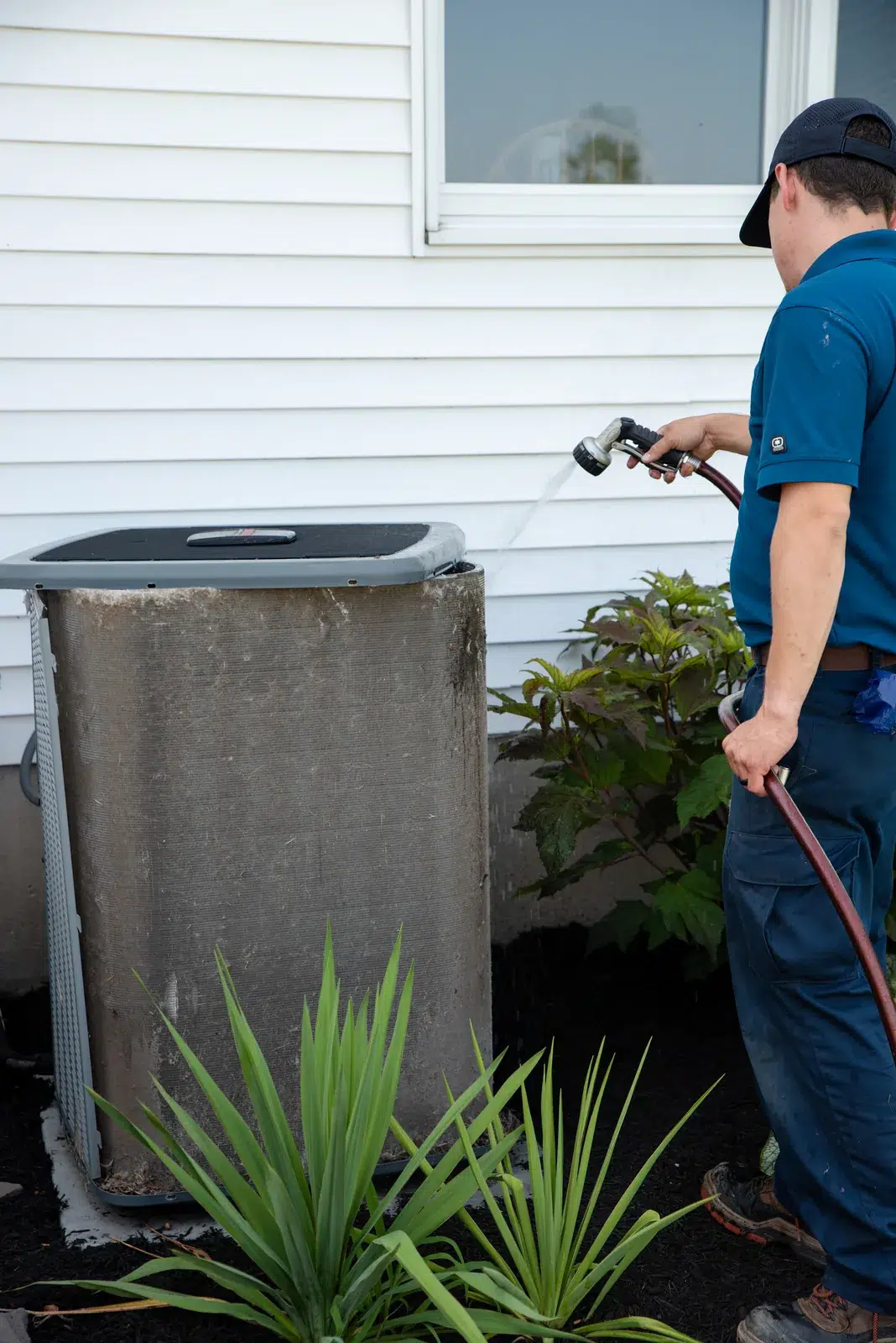 Emerald technician rinsing an outdoor air conditioning unit at a Western New York home