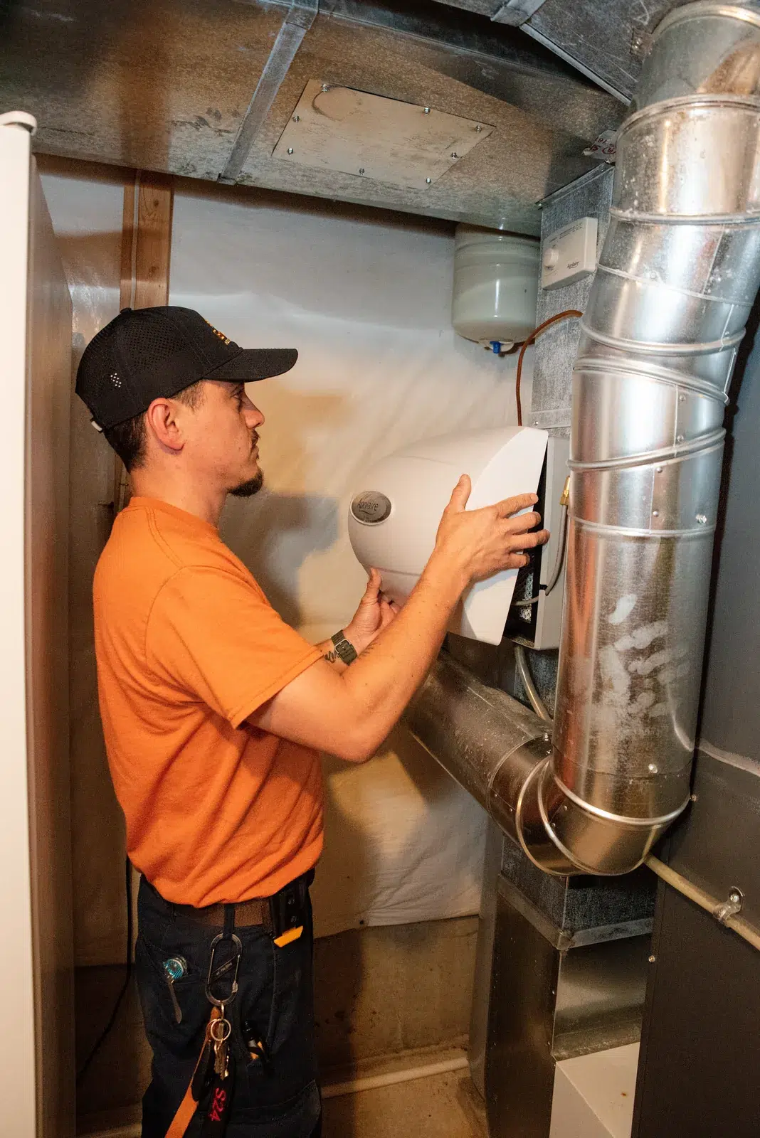Emerald technician servicing insulated ductwork and an air handler in a Western NY basement