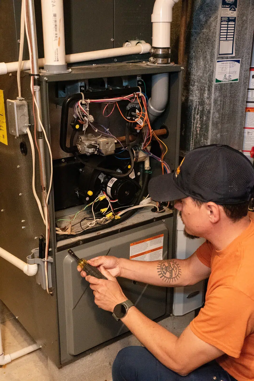 Emerald technician servicing the burner compartment of a gas furnace during a repair visit