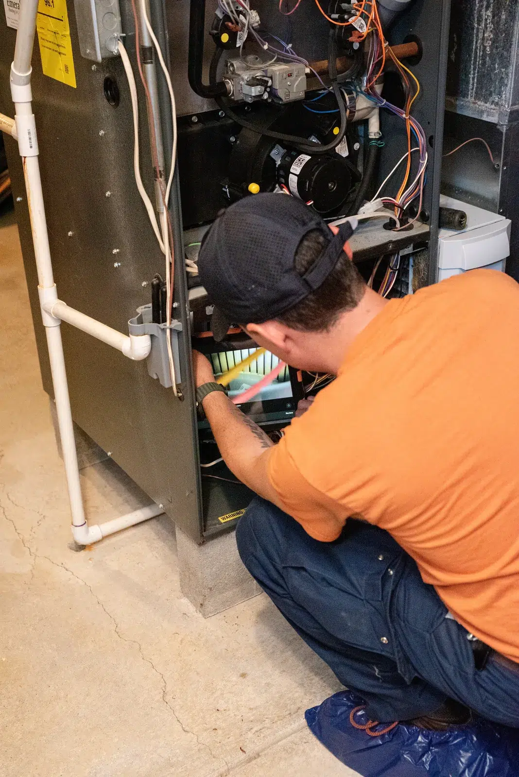 Emerald technician working inside the panel of a high-efficiency gas furnace