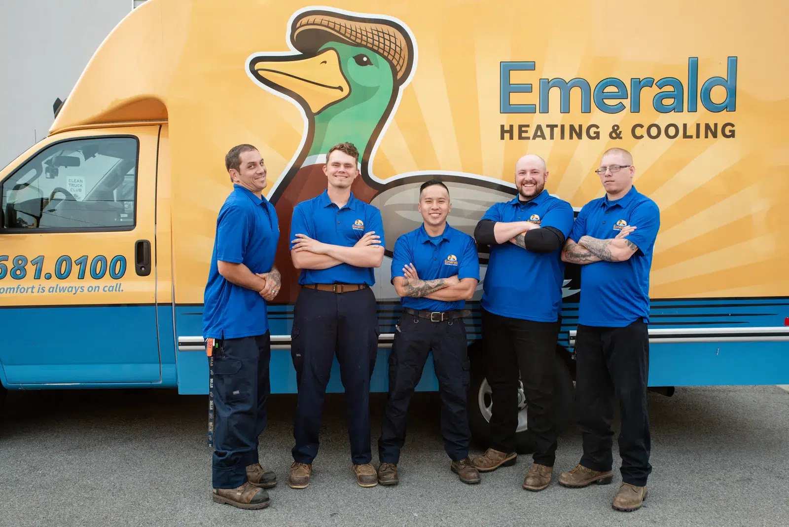 Emerald Heating & Cooling technicians standing together in front of a branded service van
