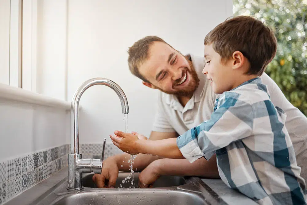 happy family dad and son washing hands in kitchen sink