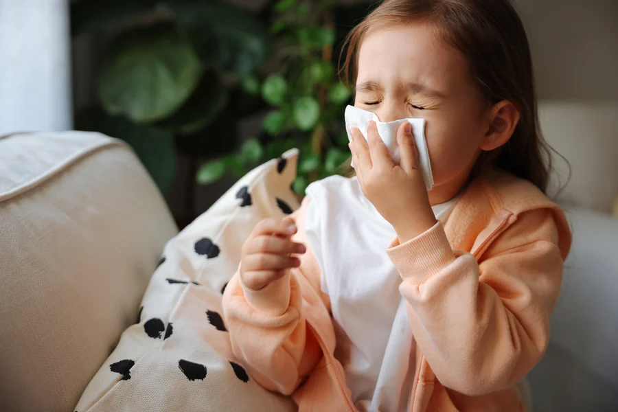 girl sneezing due to indoor allergies